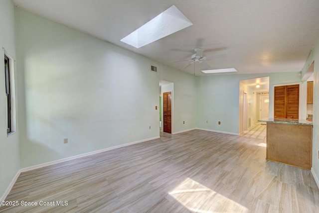 5320 Shadwell Ave, Cocoa, FL 32926 - unfurnished living room featuring a skylight, light wood-style floors, and a ceiling fan
