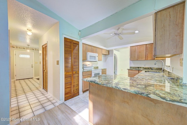 5320 Shadwell Ave, Cocoa, FL 32926 - kitchen with white appliances, stone counters, a peninsula, ceiling fan, and arched walkways