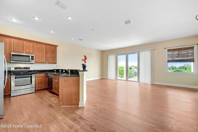 2178 Tanager Ct, Melbourne, FL 32903 - kitchen with appliances with stainless steel finishes, open floor plan, a peninsula, brown cabinetry, and a sink