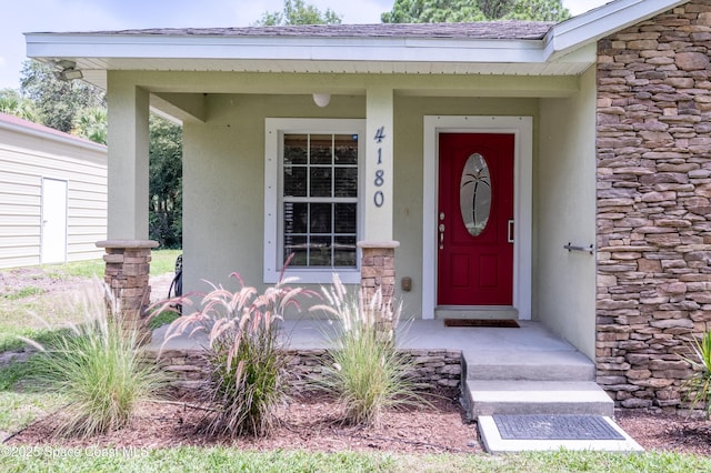 4180 Seville Ave, Cocoa, FL 32926 - view of exterior entry featuring stucco siding, stone siding, and a shingled roof
