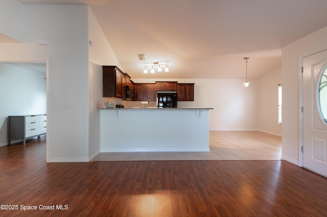 4180 Seville Ave, Cocoa, FL 32926 - kitchen with refrigerator, lofted ceiling, black microwave, a peninsula, and light stone counters