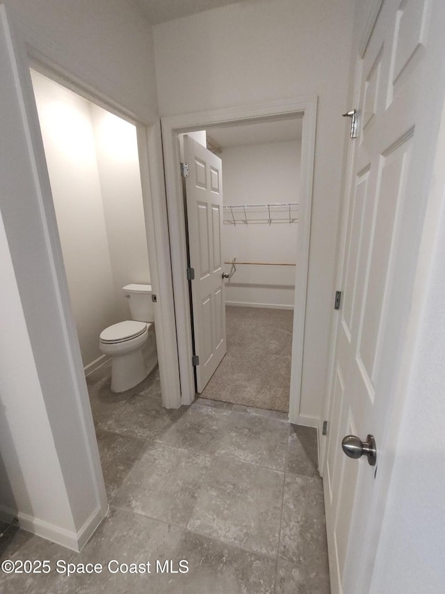 565 Sorrento Dr, Cocoa, FL 32922 - bathroom featuring toilet, baseboards, and stone finish flooring