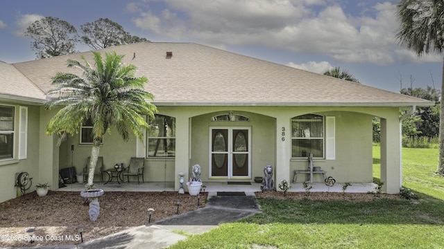 386 Valencia Rd, Melbourne, FL 32904 - view of front of home with a porch, stucco siding, a front lawn, and roof with shingles
