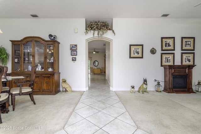 386 Valencia Rd, Melbourne, FL 32904 - interior space featuring light colored carpet, light tile patterned flooring, a glass covered fireplace, and a ceiling fan