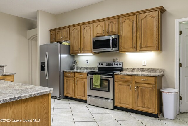386 Valencia Rd, Melbourne, FL 32904 - kitchen featuring appliances with stainless steel finishes, brown cabinets, and light tile patterned floors