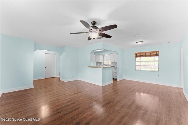 1527 Spruce Rd, Melbourne, FL 32935 - unfurnished living room with a ceiling fan, wood finished floors, arched walkways, baseboards, and a sink