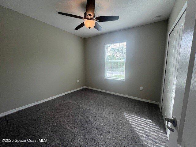 465 Hatcher St SE, Palm Bay, FL 32909 - spare room featuring a ceiling fan, dark carpet, and baseboards