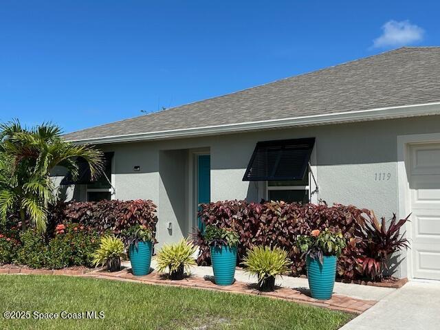 1119 Blossom Dr, Sebastian, FL 32958 - entrance to property featuring stucco siding, a shingled roof, and an attached garage