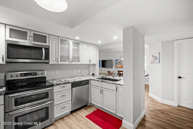 530 S Brevard Ave Unit 315, Cocoa Beach, FL 32931 - kitchen featuring stainless steel appliances, light wood-type flooring, recessed lighting, light stone counters, and glass insert cabinets