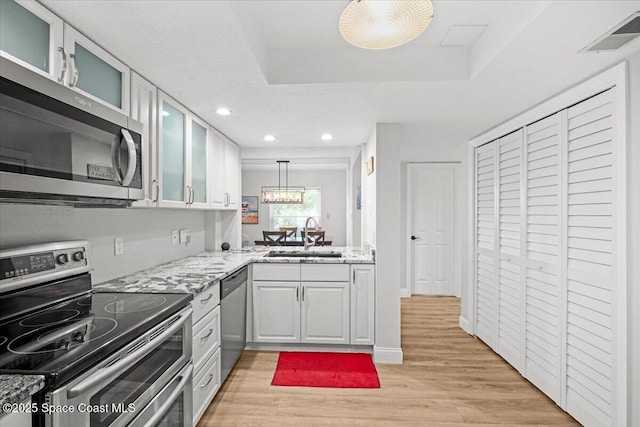 530 S Brevard Ave Unit 315, Cocoa Beach, FL 32931 - kitchen with appliances with stainless steel finishes, light wood-style floors, light stone counters, recessed lighting, and glass insert cabinets