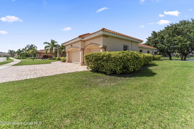3631 Thurloe Dr, Rockledge, FL 32955 - view of side of home with stucco siding, a garage, a yard, decorative driveway, and a tiled roof