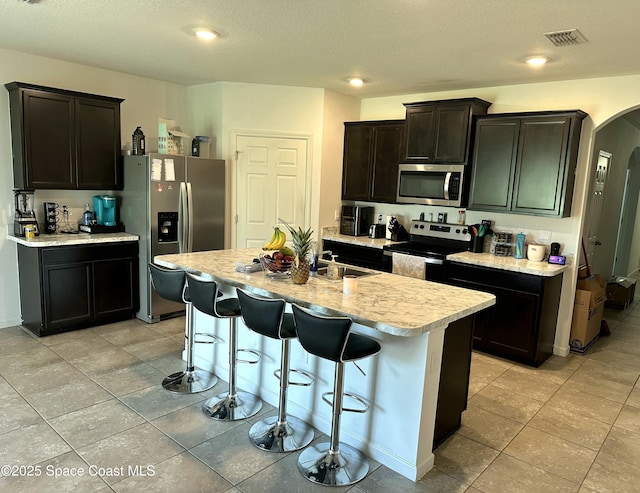 171 Knight St SE, Palm Bay, FL 32909 - kitchen featuring stainless steel appliances, arched walkways, light countertops, a kitchen bar, and light tile patterned floors