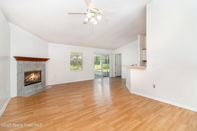 6856 Buxton Ave, Cocoa, FL 32927 - unfurnished living room featuring vaulted ceiling, a high end fireplace, light wood-style floors, a ceiling fan, and a textured ceiling