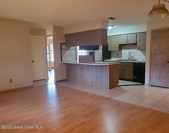 463 Spring Ln, Ocala, FL 34472 - kitchen with black dishwasher, a peninsula, a sink, and light wood-style flooring