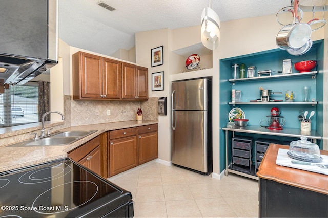 1265 Helias St NW, Palm Bay, FL 32907 - kitchen with freestanding refrigerator, electric range, a sink, brown cabinets, and decorative backsplash