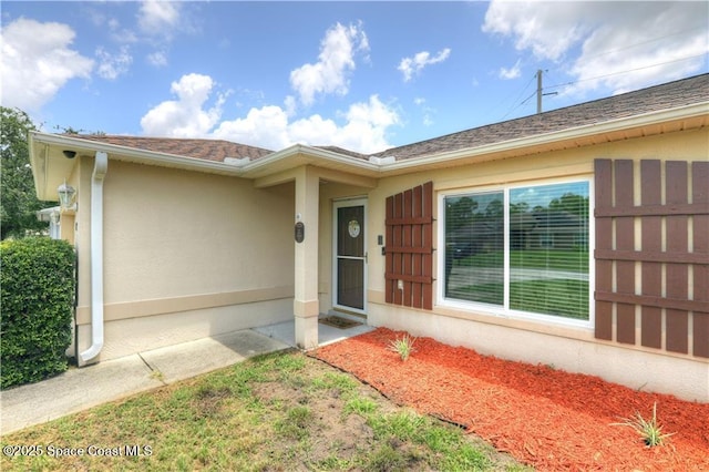 241 High Rd NW, Palm Bay, FL 32907 - view of exterior entry with stucco siding and roof with shingles