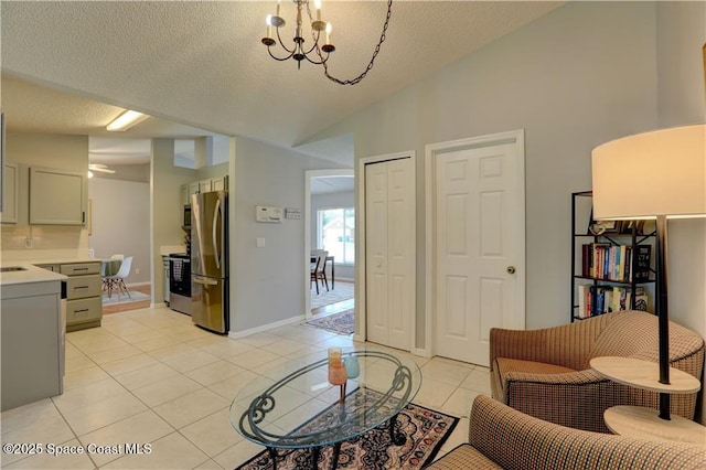 241 High Rd NW, Palm Bay, FL 32907 - living area with vaulted ceiling, a chandelier, light tile patterned flooring, a textured ceiling, and baseboards