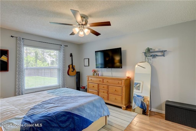 241 High Rd NW, Palm Bay, FL 32907 - bedroom with light wood finished floors, a textured ceiling, baseboards, and ceiling fan