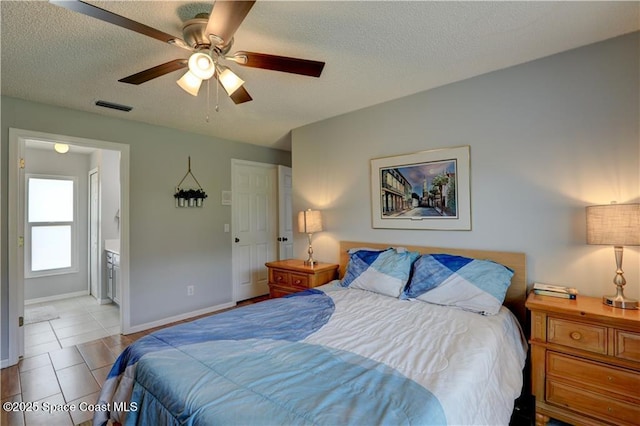 241 High Rd NW, Palm Bay, FL 32907 - bedroom featuring a textured ceiling, ensuite bath, baseboards, and a ceiling fan