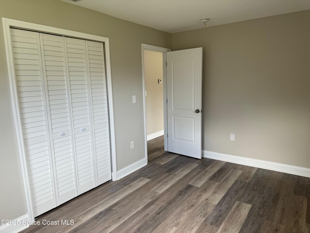 711 Sara Jane Ln, Merritt Island, FL 32952 - unfurnished bedroom with dark wood finished floors, a closet, and baseboards