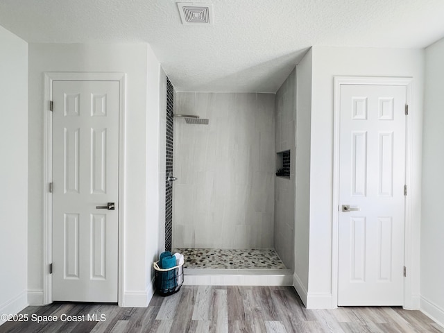 1271 Rabbit St SE, Palm Bay, FL 32909 - full bathroom featuring a tile shower, wood finished floors, baseboards, and a textured ceiling