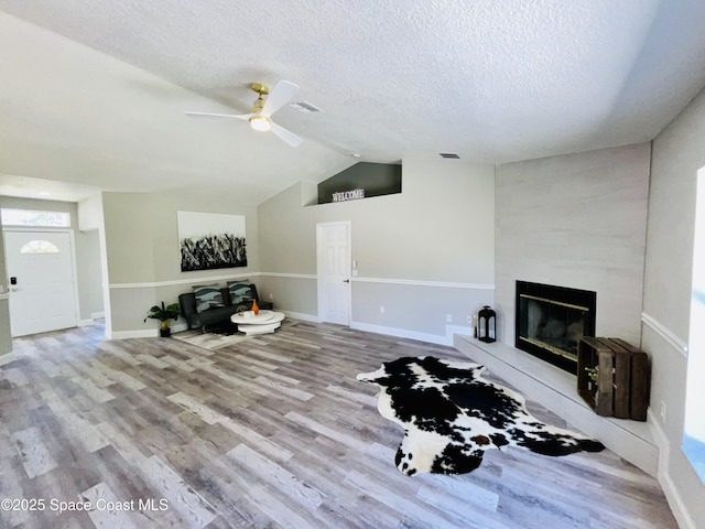 1271 Rabbit St SE, Palm Bay, FL 32909 - living room featuring ceiling fan, wood finished floors, a textured ceiling, lofted ceiling, and a tiled fireplace