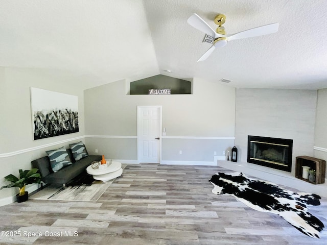 1271 Rabbit St SE, Palm Bay, FL 32909 - living area with wood finished floors, lofted ceiling, a textured ceiling, ceiling fan, and a large fireplace