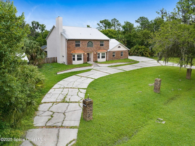 2575 Cox Rd, Cocoa, FL 32926 - view of front of property with a chimney, a standing seam roof, brick siding, concrete driveway, and a metal roof