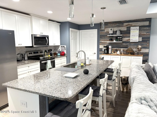 259 Wilton Ave SW, Palm Bay, FL 32908 - kitchen with stainless steel appliances, a sink, wood finished floors, white cabinets, and recessed lighting