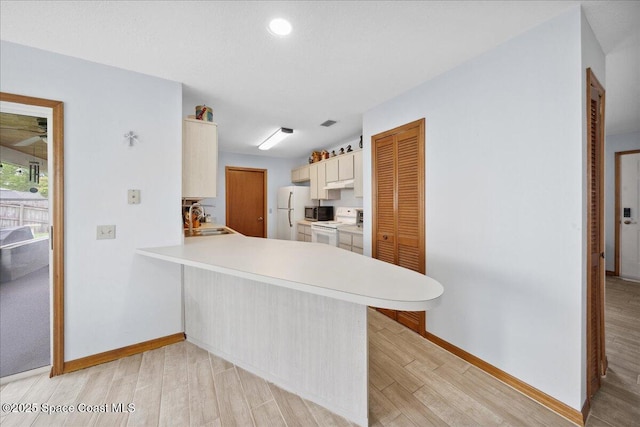 5997 Jenkins Ave, Cocoa, FL 32927 - kitchen featuring white appliances, light countertops, light wood-style flooring, a peninsula, and recessed lighting