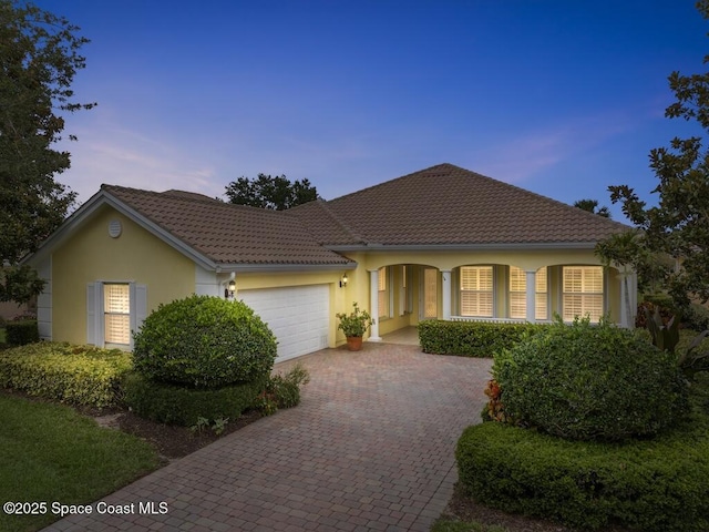 5422 Barbados Sq, Vero Beach, FL 32967 - view of front of home with decorative driveway, an attached garage, stucco siding, covered porch, and a tile roof