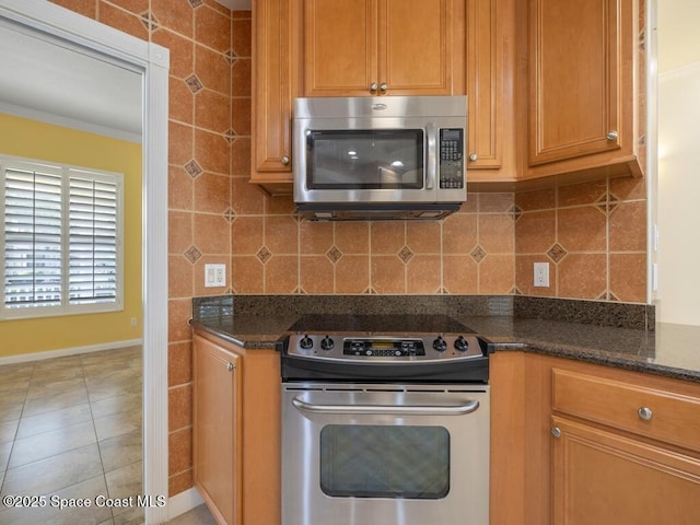 5422 Barbados Sq, Vero Beach, FL 32967 - kitchen with appliances with stainless steel finishes, backsplash, dark stone countertops, brown cabinets, and baseboards