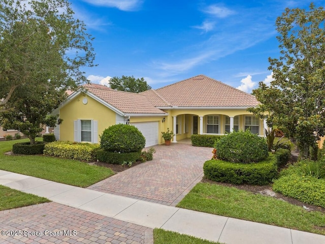 5422 Barbados Sq, Vero Beach, FL 32967 - mediterranean / spanish-style home with an attached garage, stucco siding, a front yard, decorative driveway, and a porch