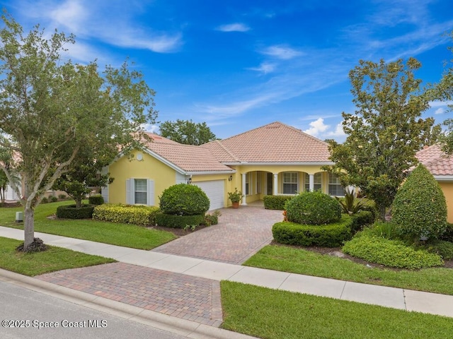 5422 Barbados Sq, Vero Beach, FL 32967 - mediterranean / spanish-style home featuring a garage, decorative driveway, stucco siding, a front lawn, and a tile roof