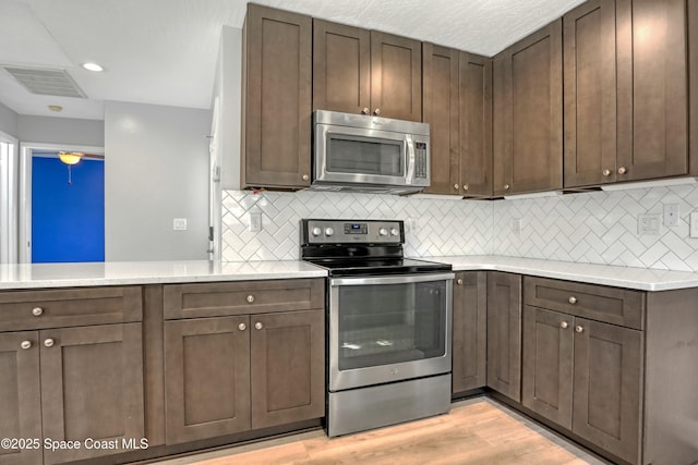 1020 S Fork Cir, Melbourne, FL 32901 - kitchen featuring stainless steel appliances, light countertops, decorative backsplash, light wood-style flooring, and dark brown cabinetry