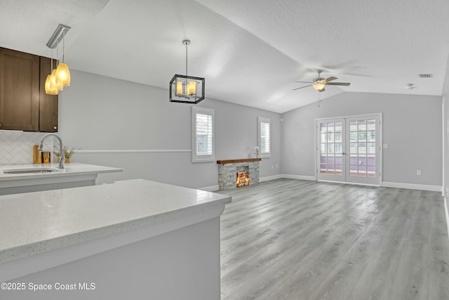 1020 S Fork Cir, Melbourne, FL 32901 - kitchen with a ceiling fan, hanging light fixtures, backsplash, lofted ceiling, and light wood-style flooring