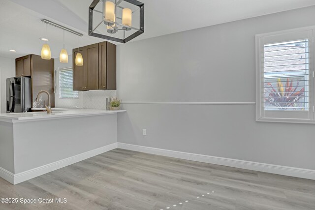 1020 S Fork Cir, Melbourne, FL 32901 - kitchen featuring freestanding refrigerator, tasteful backsplash, light wood-type flooring, light countertops, and pendant lighting