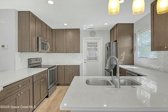1020 S Fork Cir, Melbourne, FL 32901 - kitchen featuring appliances with stainless steel finishes, decorative backsplash, light wood-type flooring, light stone countertops, and recessed lighting