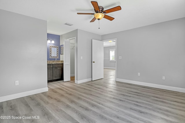 1020 S Fork Cir, Melbourne, FL 32901 - unfurnished bedroom featuring light wood-type flooring, connected bathroom, a ceiling fan, and a closet