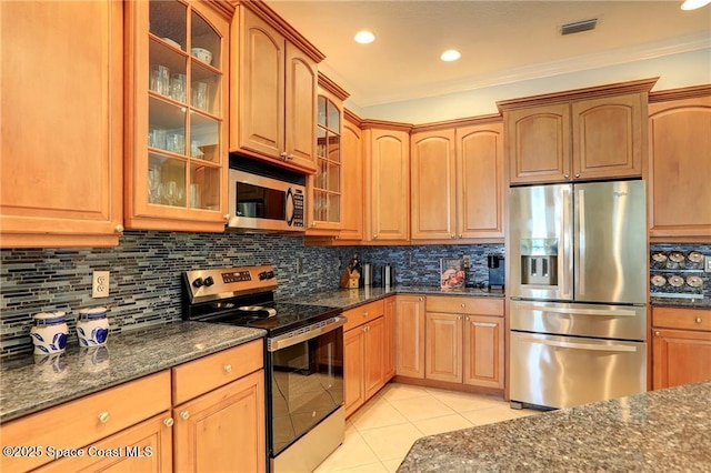 1641 Galilean Ln, Sebastian, FL 32958 - kitchen featuring appliances with stainless steel finishes, light tile patterned floors, dark stone counters, glass insert cabinets, and decorative backsplash