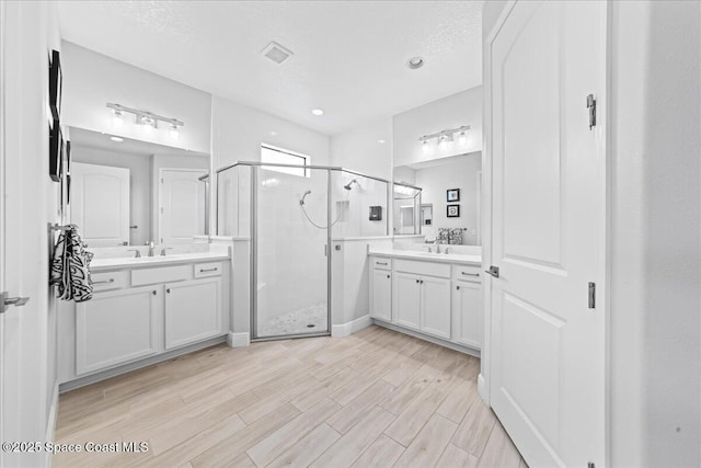 7917 Dobre Way, Melbourne, FL 32940 - bathroom featuring a shower stall, two vanities, and wood finished floors
