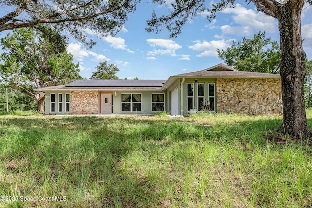 1940 Leah Star Rd, Astor, FL 32102 - rear view of house with stone siding, roof mounted solar panels, a garage, and stucco siding