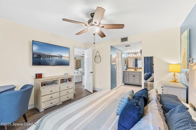 200 International Dr Unit 817, Cape Canaveral, FL 32920 - bedroom featuring wood finished floors, ensuite bathroom, a sink, baseboards, and a textured ceiling