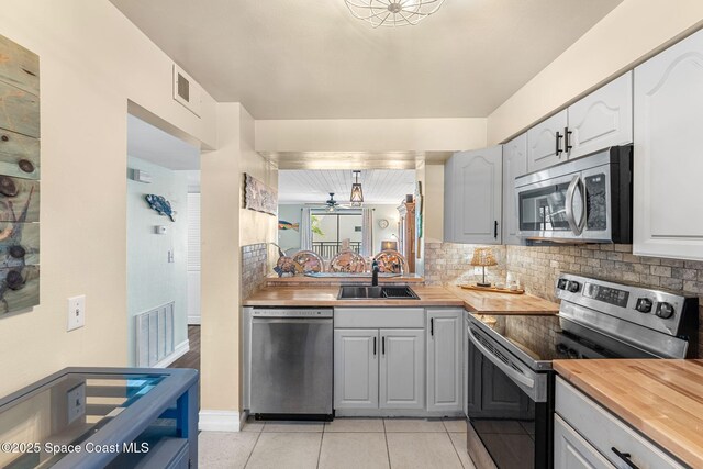 200 International Dr Unit 817, Cape Canaveral, FL 32920 - kitchen with appliances with stainless steel finishes, a sink, butcher block countertops, decorative backsplash, and light tile patterned floors