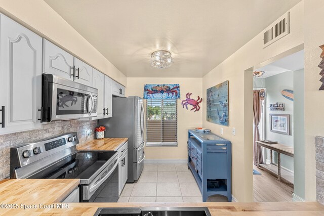 200 International Dr Unit 817, Cape Canaveral, FL 32920 - kitchen featuring appliances with stainless steel finishes, butcher block counters, backsplash, baseboards, and white cabinets