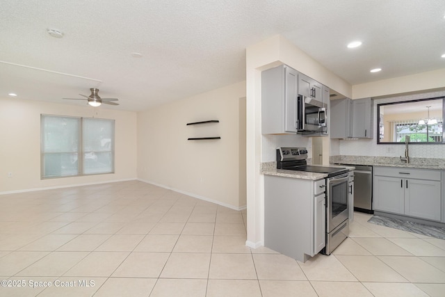 1935 Conway Rd Unit A4, Orlando, FL 32812 - kitchen with appliances with stainless steel finishes, gray cabinets, a sink, ceiling fan, and light stone counters