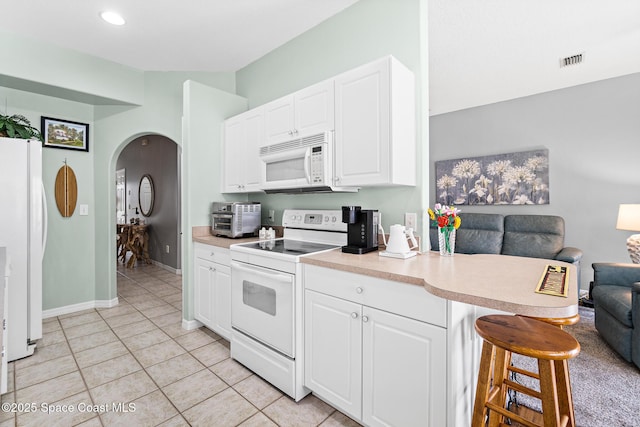 5201 Ocean Beach Blvd Unit 4, Cocoa Beach, FL 32931 - kitchen with white appliances, open floor plan, arched walkways, a kitchen bar, and white cabinets