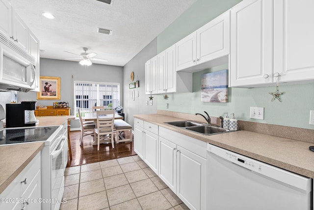 5201 Ocean Beach Blvd Unit 4, Cocoa Beach, FL 32931 - kitchen with white appliances, a ceiling fan, white cabinetry, light tile patterned floors, and a textured ceiling