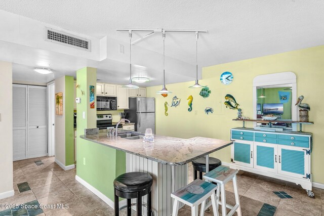 4800 Ocean Beach Blvd Unit 218, Cocoa Beach, FL 32931 - kitchen with stainless steel appliances, rail lighting, a breakfast bar area, a peninsula, and light stone countertops