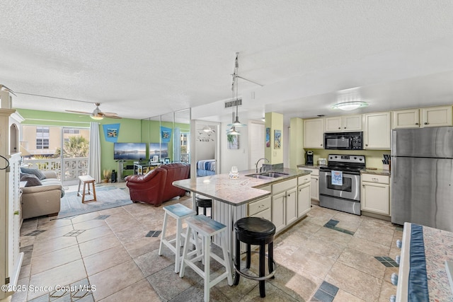 4800 Ocean Beach Blvd Unit 218, Cocoa Beach, FL 32931 - kitchen with stainless steel appliances, open floor plan, cream cabinetry, a ceiling fan, and a textured ceiling